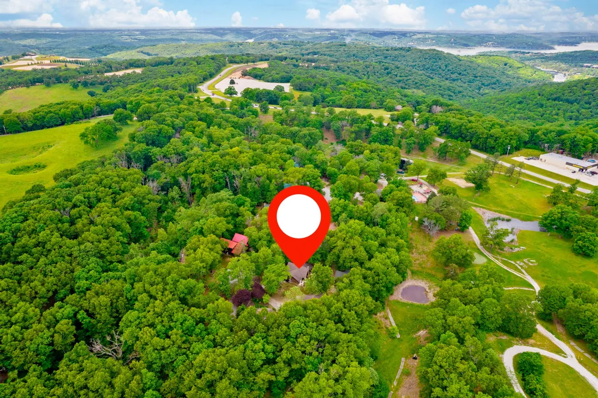 This exterior image features dense greenery, scattered houses, and a serene pond, creating an inviting natural setting. The open spaces and winding paths suggest an environment ideal for leisurely strolls, outdoor exploration, and nature walks.