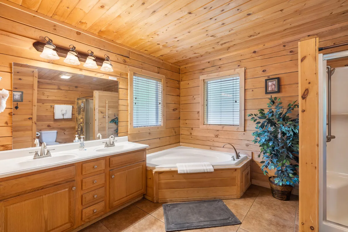 A serene bathroom with a double vanity, large jacuzzi tub, framed mirror, and touches of greenery. The space feels spa-like, bright, and perfect for unwinding with a luxurious soak.