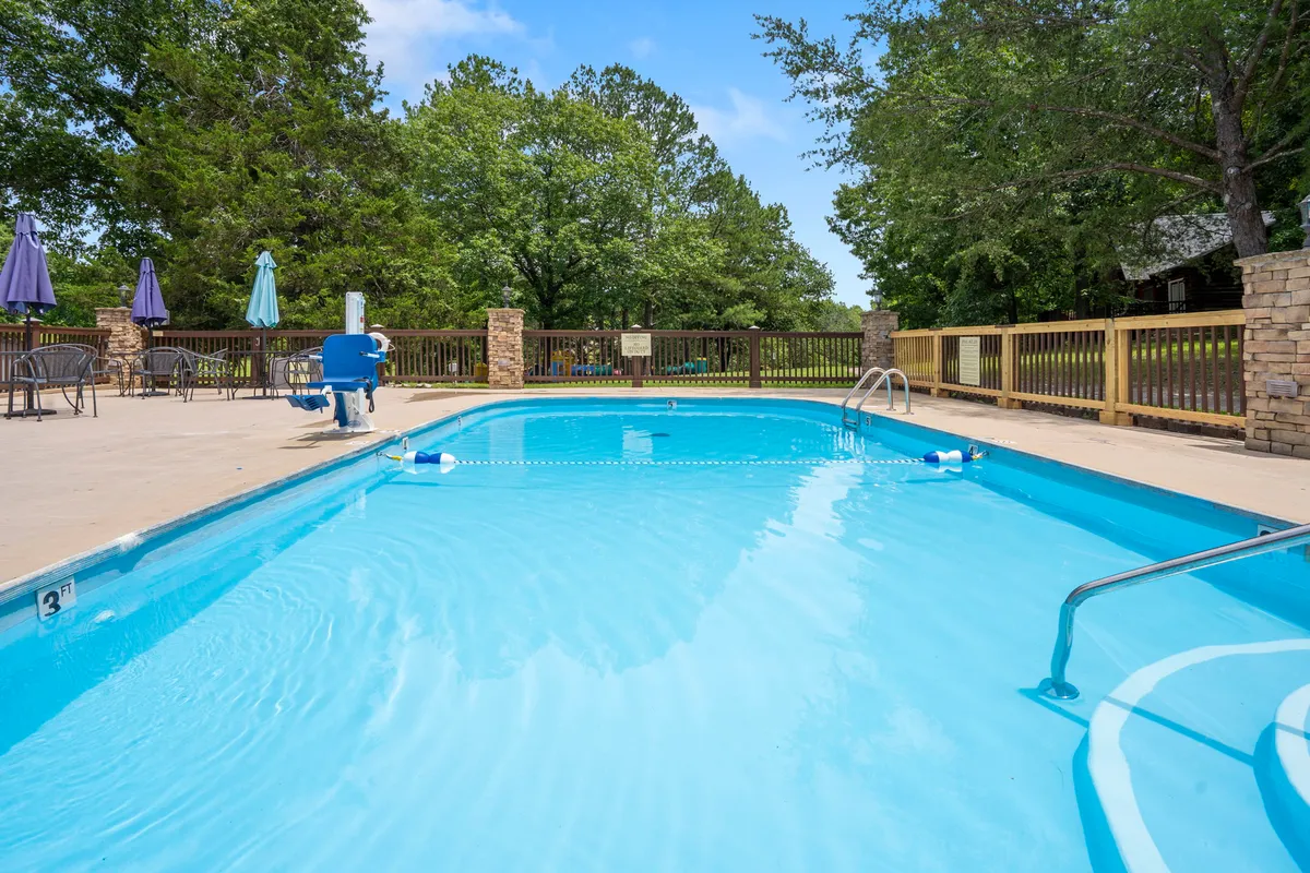 A sparkling outdoor swimming pool is surrounded by lush green trees and several lounge chairs, inviting groups to swim or relax together in the sun. The setup suggests ample opportunities for gatherings, laughter, and summer fun.